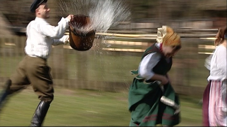 Mężczyzna biegnie z wiadrem wody za kobietami